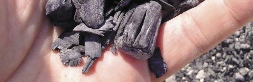 Sample of pyrolysis ash residue held in a hand, showing dark charcoal-like fragments