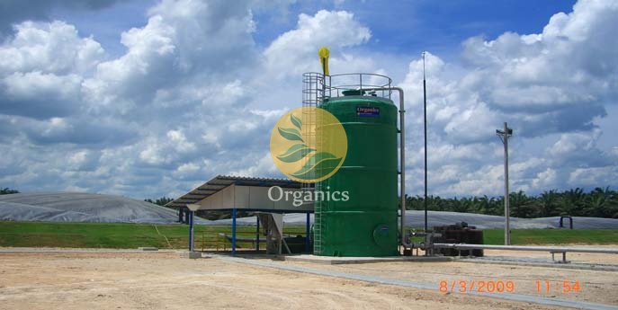 Technician inspecting anaerobic digestion and biogas piping infrastructure at a palm oil processing facility